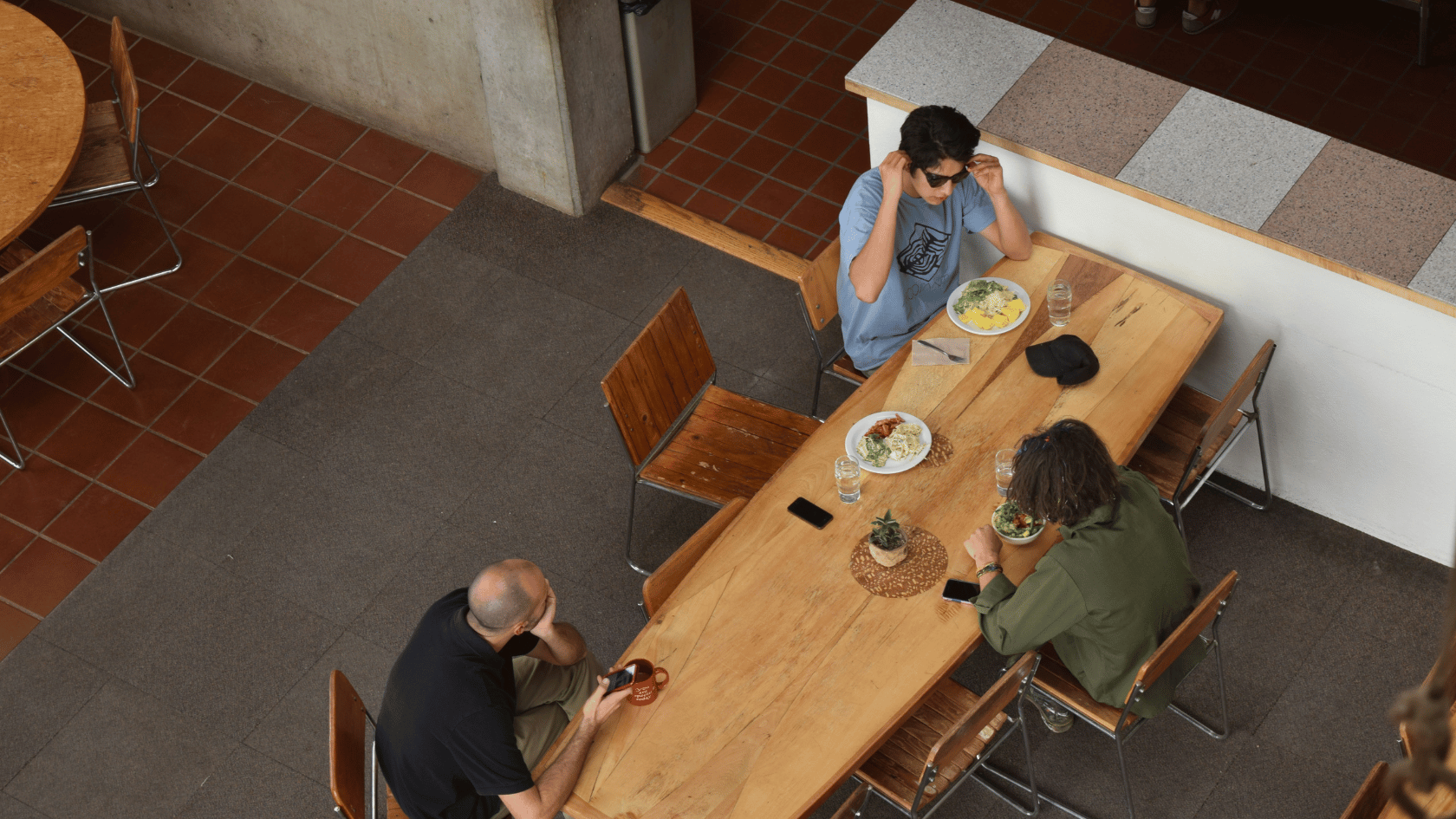 People sitting at the long wooden table having lunch